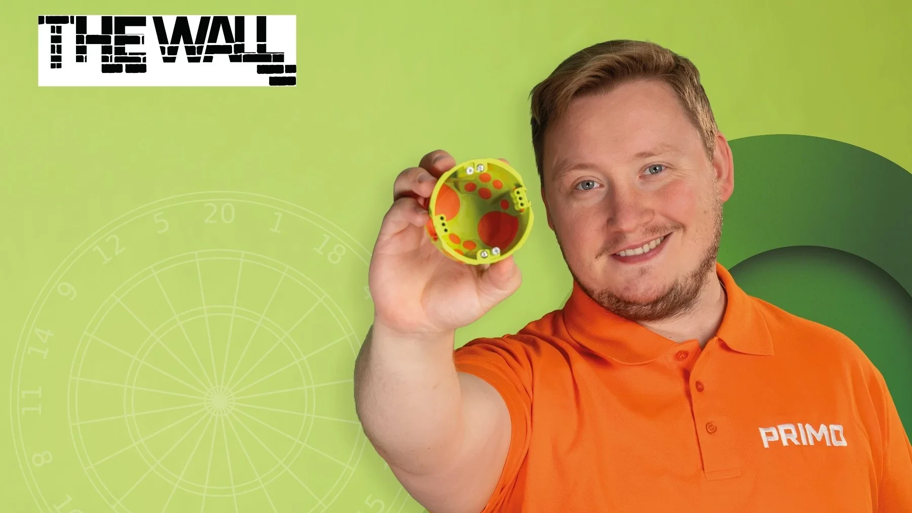 Martin Schindler im PRIMO-Poloshirt hält eine Qnect Hohlwanddose, daneben das The-Wall-Logo